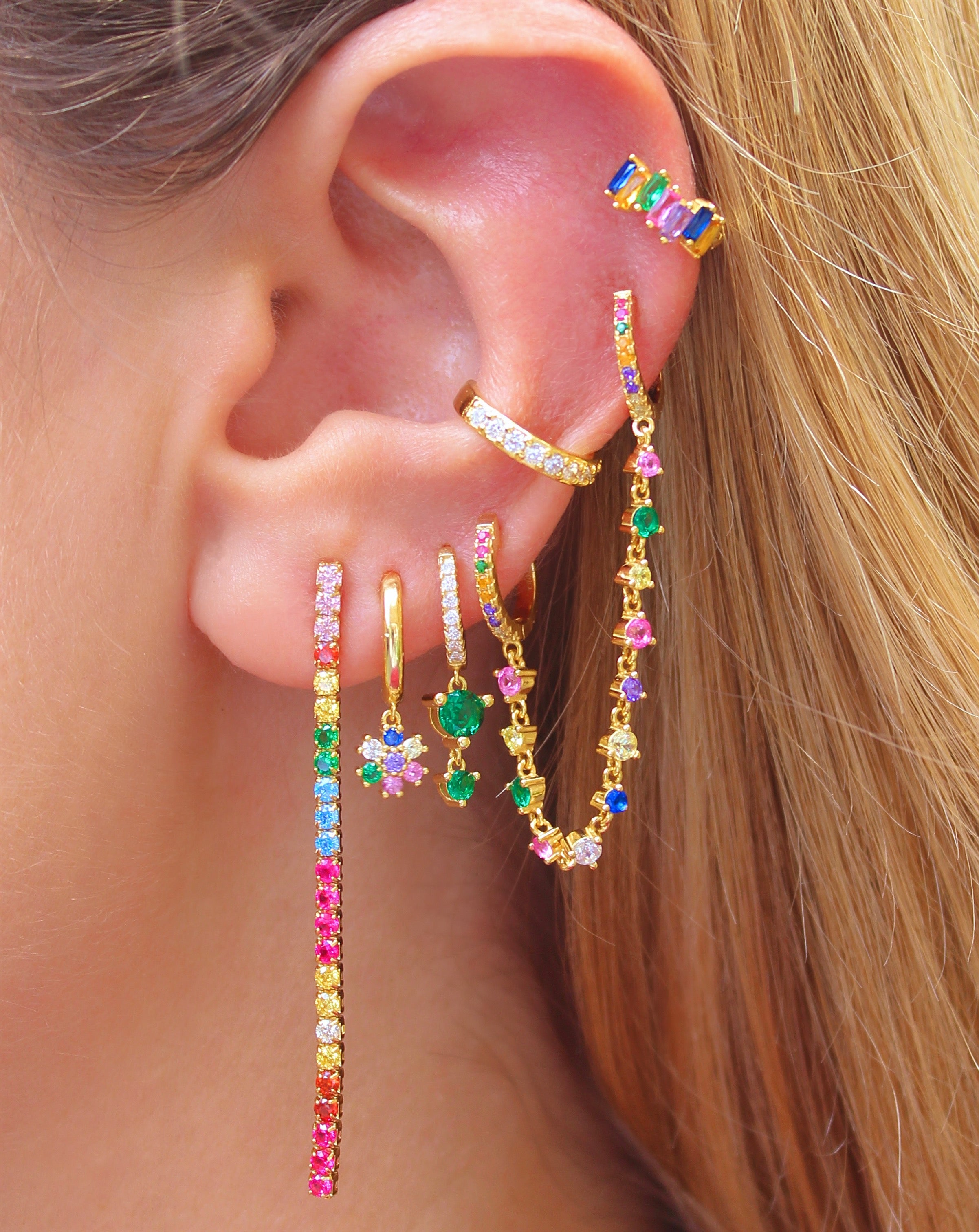 Aro Huggie dorado con flor de margarita y circonitas múltiples