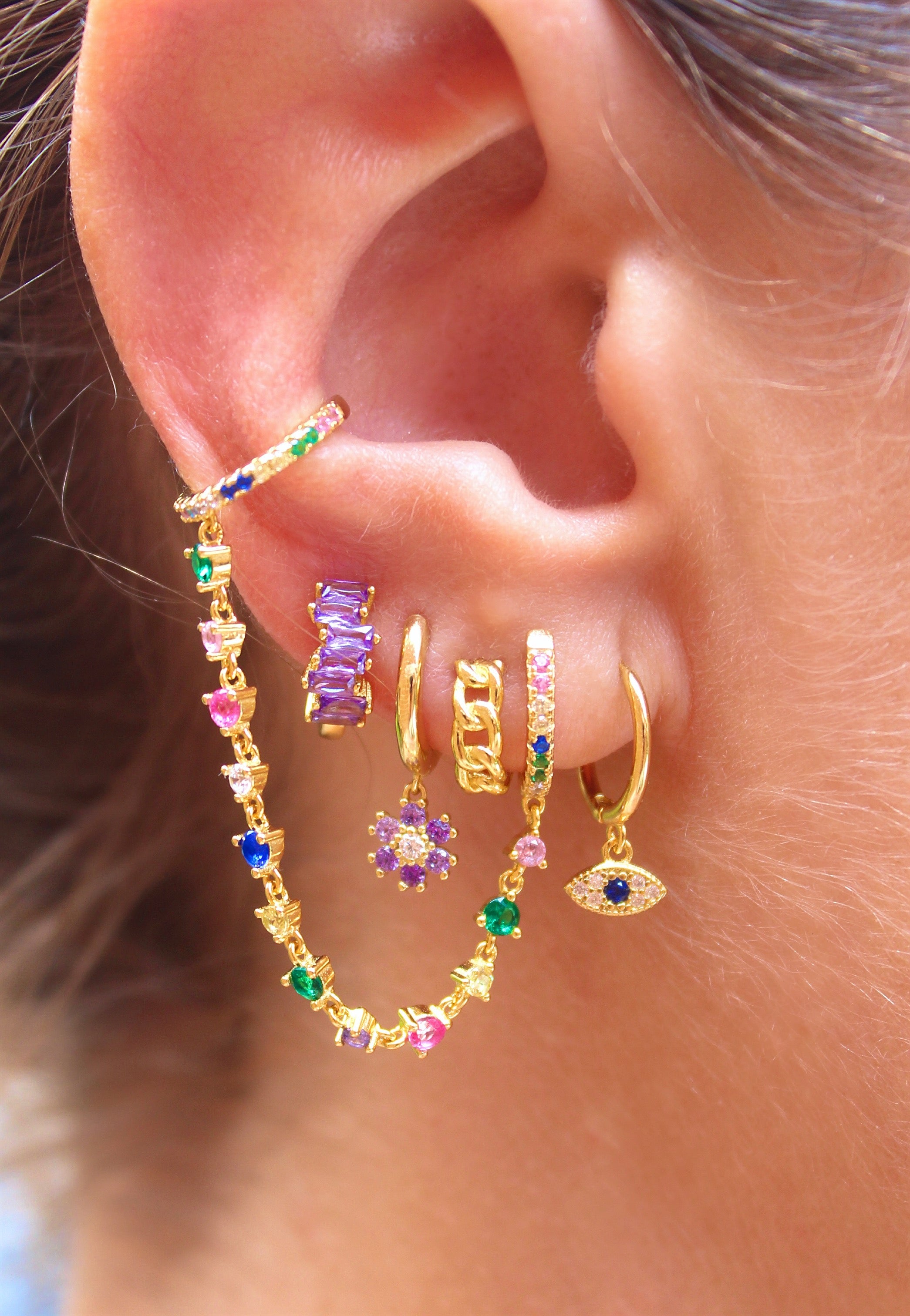 Aro Huggie dorado con flor de margarita y circonita lila