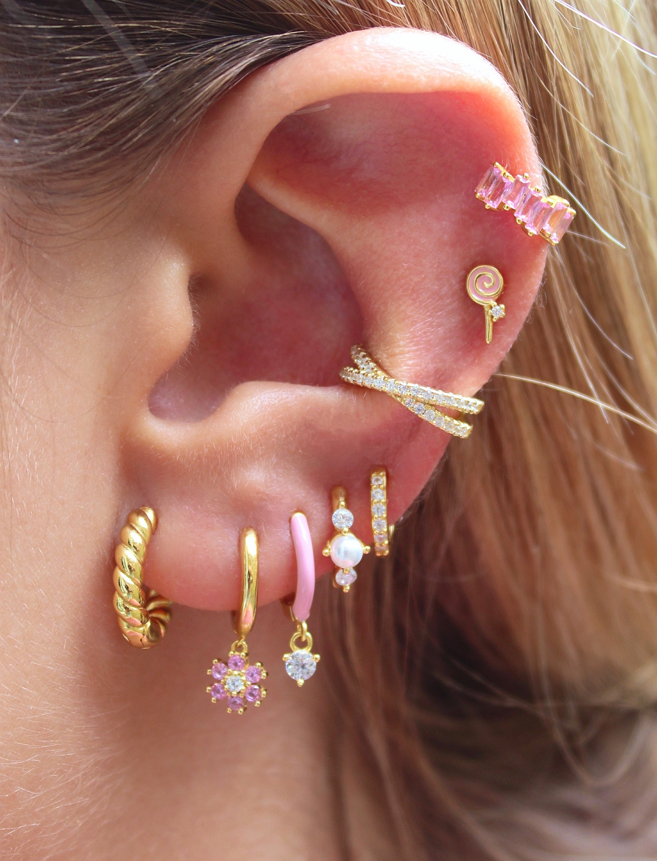 Aro Huggie dorado con flor de margarita rosa y circonitas cúbicas