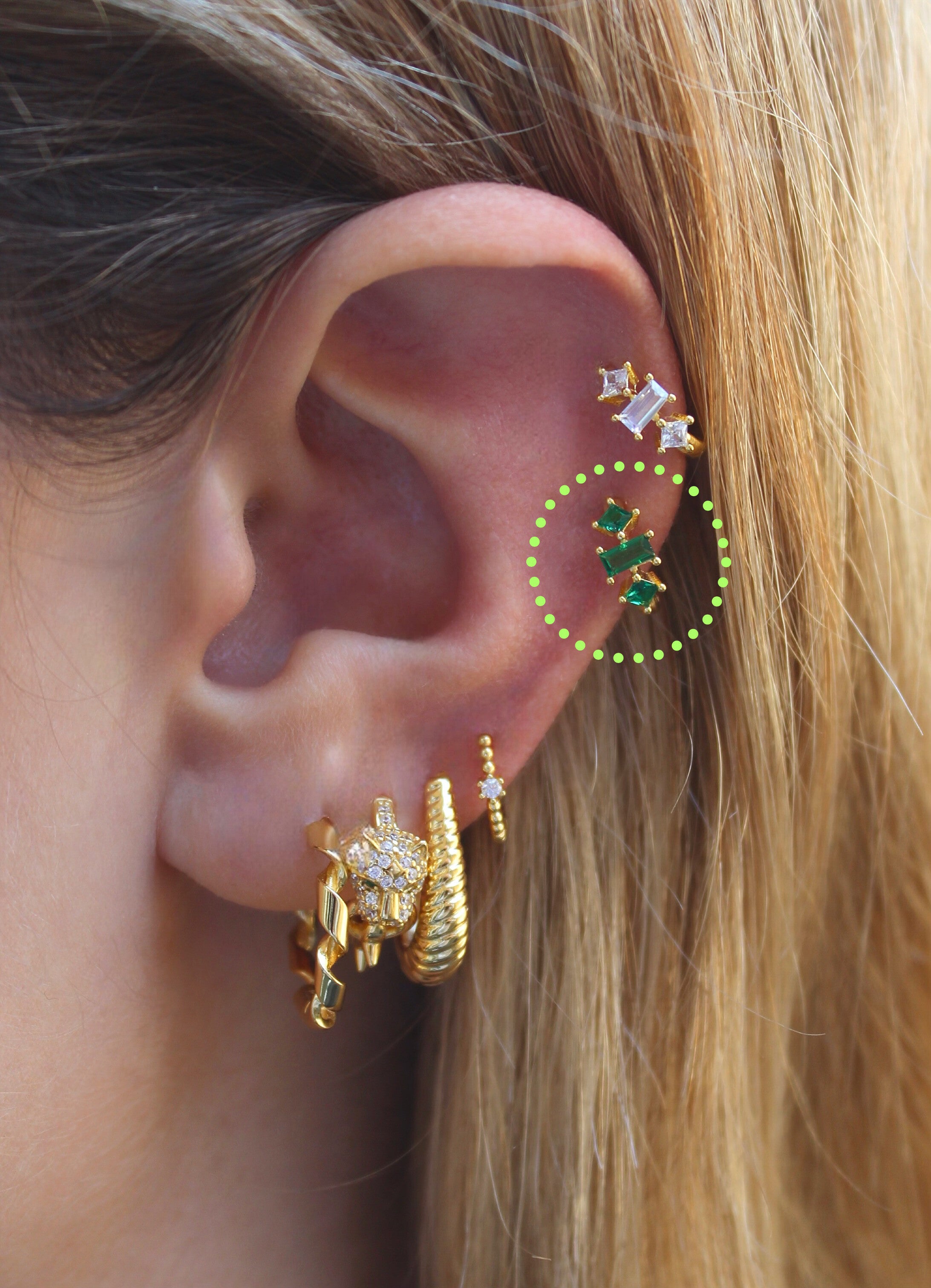 Aro Huggie dorado con triple circonita verde y trilogía